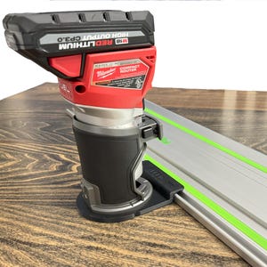 May include: A red and black Milwaukee M18 FUEL compact router with a black base is shown. The router is attached to a silver and green guide rail. The battery says "M18 REDLITHIUM HIGH OUTPUT CP3.0".