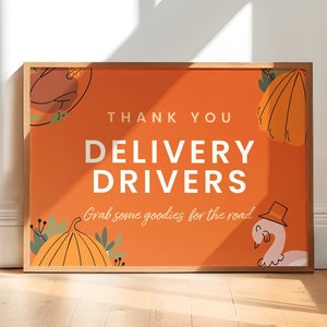 May include: A framed orange sign with the text "THANK YOU DELIVERY DRIVERS" in white. The sign also includes the phrase "Grab some goodies for the road" in a script font. Decorative pumpkins and a turkey are featured.