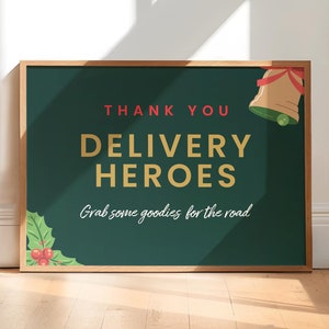 May include: A green chalkboard sign with a wooden frame, reading "Thank You Delivery Heroes. Grab some goodies for the road."  A gold bell with a red ribbon is in the top right corner, and a green holly sprig with red berries is in the bottom left corner.