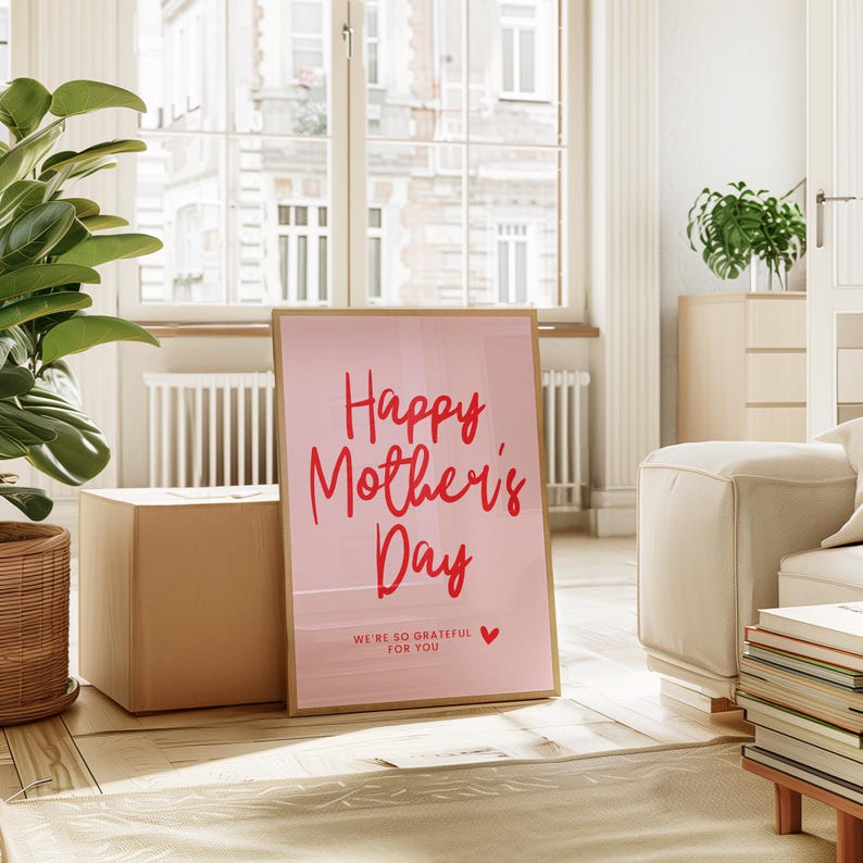 May include: A pink poster with a wooden frame that says "Happy Mother's Day" in red cursive lettering. The poster also says "We're so grateful for you" in smaller red lettering with a small red heart.