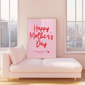 May include: A pink framed poster with the text "Happy Mother's Day" in red script. The poster also includes the text "We're so grateful for you" in smaller red text with a small red heart.