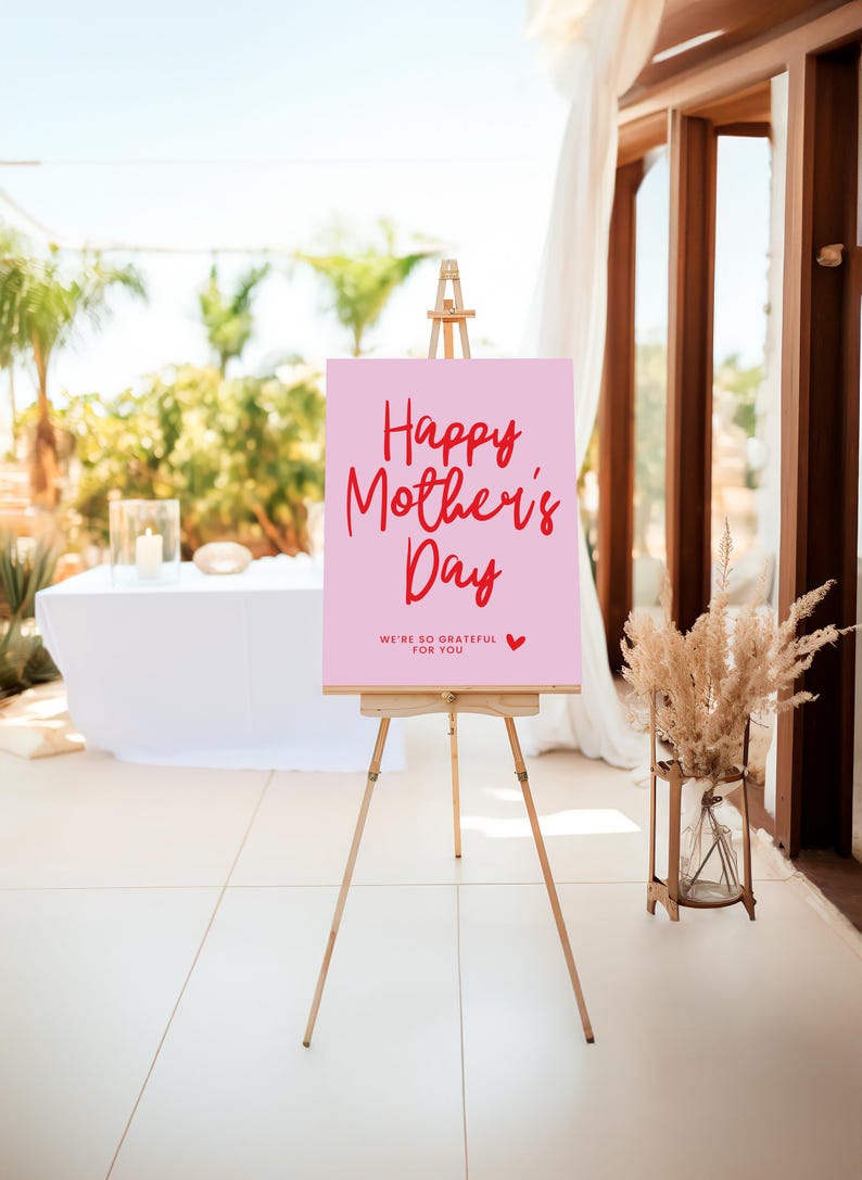 May include: A pink sign with the text "Happy Mother's Day" in red script font. The sign also includes the text "We're so grateful for you" in smaller red font with a small red heart.