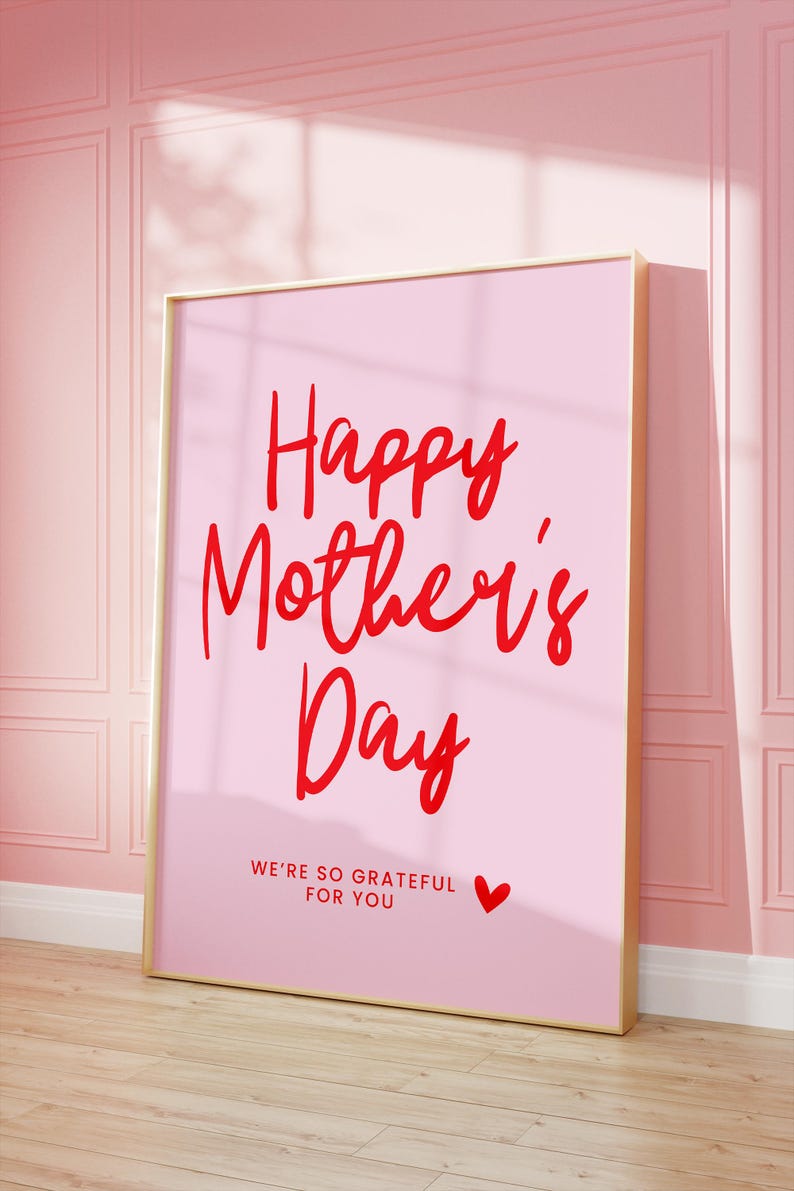 May include: A pink framed poster with the text "Happy Mother's Day" in red cursive lettering. The poster also includes the text "We're so grateful for you" in red lettering with a small red heart.