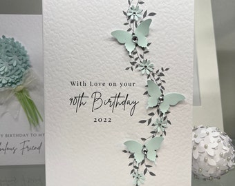 May include: A white card with a light blue butterfly design and the text "With Love on your 90th Birthday 2022".