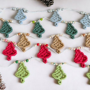 May include: A festive Christmas tree garland featuring handmade macrame trees in various colors, including blue, green, red, and tan. The trees are strung together with a light blue cord and interspersed with wooden beads and decorative accents. A charming holiday decoration.