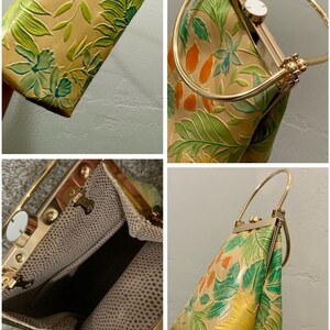 May include: A tan handbag with a floral design in green, blue, and orange. The bag has a gold-colored metal frame and handle. The interior lining is a dotted pattern.