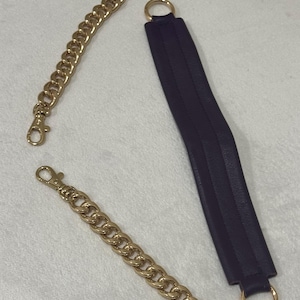 May include: A set of bag accessories including two gold-toned metal chain straps with lobster claw clasps and one long, rectangular dark purple leather strap featuring a gold-toned metal ring attached to each end for secure attachment.