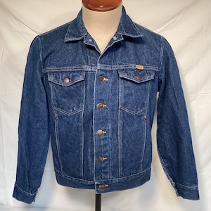 May include: A classic blue denim jacket with a button-up front, two chest pockets, and two side pockets. The jacket has a collared neckline and long sleeves. The jacket is displayed on a mannequin.