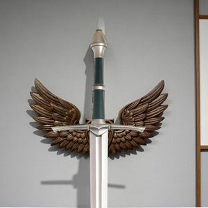 Könnte beinhalten: Ein dekoratives Schwert mit einer silbernen Klinge und einem dunkelgrünen Griff. Das Schwert ist an einer Wand mit bronzefarbenen Flügeln auf beiden Seiten befestigt. Der Knauf und der Parier sind silberfarben.