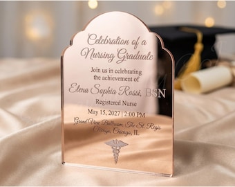 May include: A rose gold acrylic invitation for a nursing graduate. The text reads "Celebration of a Nursing Graduate" and includes the graduate's name, date, time, and location. A caduceus symbol is at the bottom.