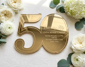 May include: A gold-colored, mirrored acrylic invitation for a 50th birthday celebration. The invitation features the number "50" and includes event details: "Celebrating Fifty," the name "LINDA MARIE CARTER," date, time, and location.