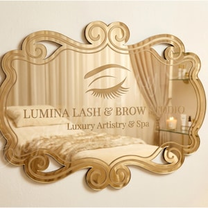 May include: A gold-toned mirror with an ornate, scrolled frame. The mirror reflects a spa-like interior with a bed, curtains, and the text "Lumina Lash & Brow Studio, Luxury Artistry & Spa" and an eye graphic.