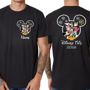 A black t-shirt with a Disney-themed design featuring Mickey Mouse and Minnie Mouse characters, along with the text "Disney Trip 2020" printed on the back.