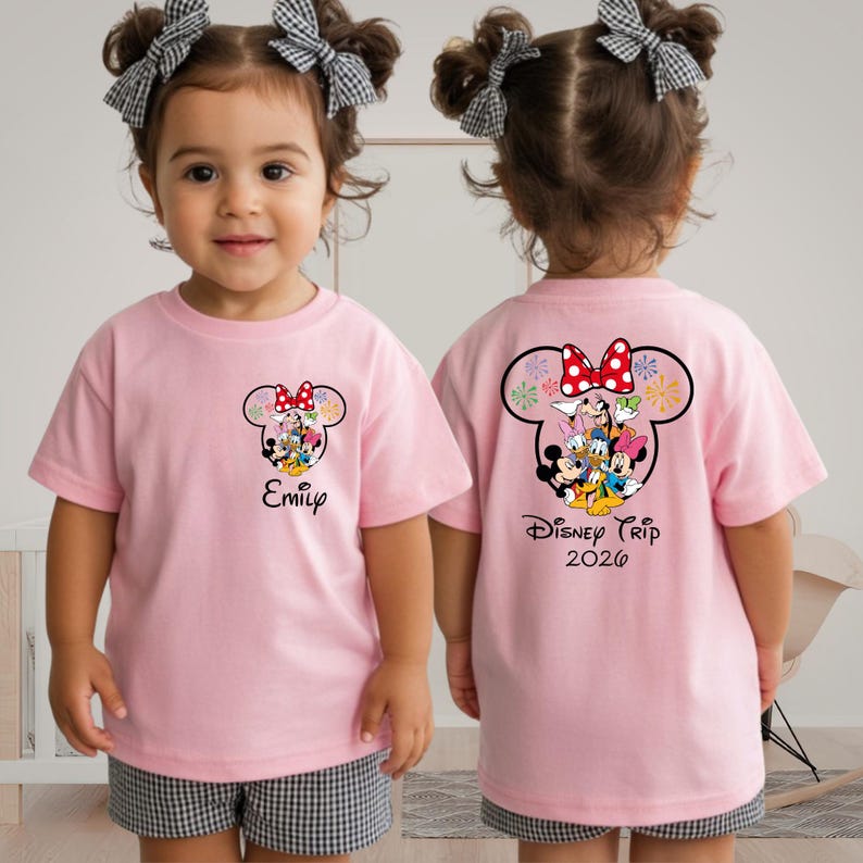 A young girl wearing a pink t-shirt with a Disney character design and the text "Disney Trip 2020" printed on the back.