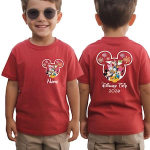 A young boy wearing a red Disney-themed t-shirt with Mickey Mouse and Minnie Mouse designs, along with the text "Disney Trip 2020".