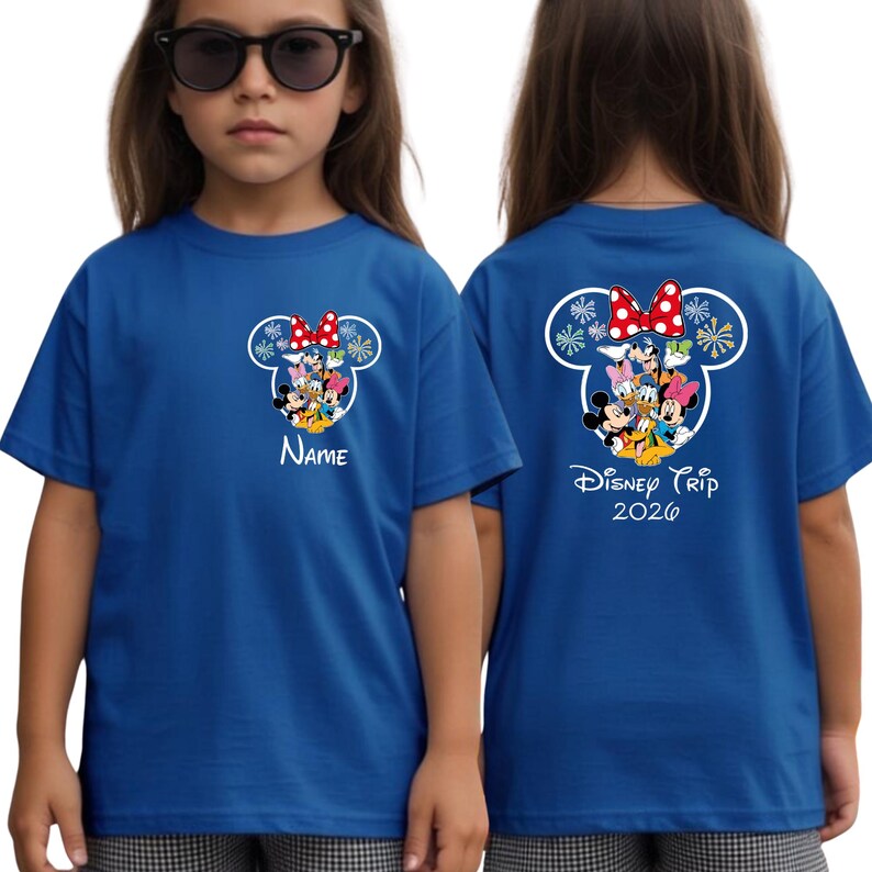 A young girl wearing a blue t-shirt with a Disney character design and the text "Disney Trip 2020" printed on the back.