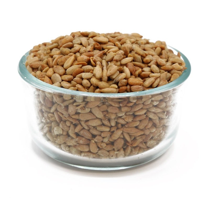 May include: A glass bowl filled with hulled sunflower seeds. The seeds are a light brown color and appear to be roasted.