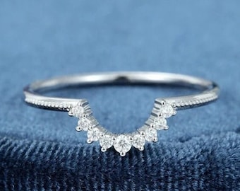May include: A delicate silver ring with a curved band and a row of small, sparkling diamonds set in a crescent shape.
