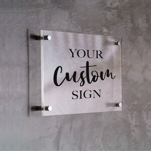 May include: A clear acrylic sign with the text "YOUR custom SIGN" in black lettering.