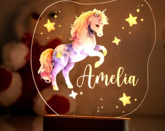 May include: A whimsical night light featuring a colorful unicorn with stars and the name Amelia. The light is made of clear acrylic and has a wooden base.