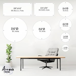 May include: A white wall with various sizes of round mirrors with black outlines and measurements in inches and centimeters. The mirrors are arranged in a grid pattern. There is a wooden table and a gray chair in the foreground.