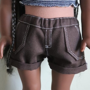 May include: Brown denim shorts with white stitching and rolled up cuffs. The shorts have a relaxed fit and are made of a soft, comfortable fabric.