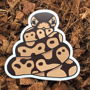 Może przedstawiać: Naklejka z kreskówki przedstawiająca brązowego i beżowego węża zwiniętego w kłębek. Wąż ma duże, czarne oczy i słodki wyraz twarzy.