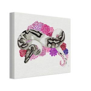 May include: A canvas print featuring a watercolour painting of a snake with a black and grey pattern, surrounded by pink, purple, and red flowers. The artwork is set against a white background, enhancing the colours. The snake and floral details add to the artwork's appeal.