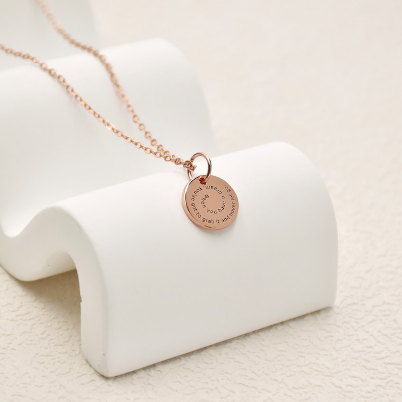May include: A rose gold necklace with a round pendant that reads "When you have a dream, grab it and never let it go."