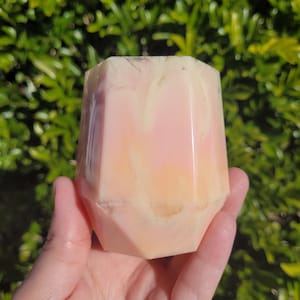 May include: A pink and yellow geometric resin planter with a marbled effect. The planter has a unique, faceted shape.