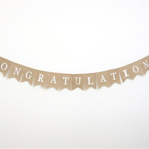 May include: A burlap banner with the word "Congratulations" printed in white letters.