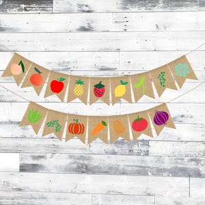 May include: A burlap banner with a string of flags featuring various fruits and vegetables. The flags are decorated with images of a peach, apple, pineapple, strawberry, lemon, carrot, pumpkin, tomato, onion, and a sprig of greenery.