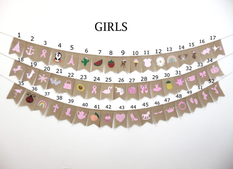 May include: A burlap banner with pink and white embroidered designs. The banner has 52 flags with numbers 1 through 52. The banner says "GIRLS" at the top.