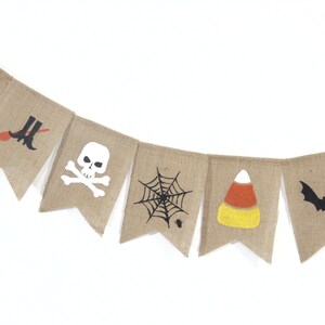 Puede incluir: Una guirnalda de arpillera con dise&ntilde;os de Halloween. Cada bander&iacute;n presenta un gr&aacute;fico diferente, que incluye un sombrero de bruja, una escoba y botas, una calavera y huesos cruzados, una telara&ntilde;a, un caramelo de ma&iacute;z y un murci&eacute;lago.