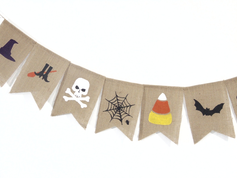 Puede incluir: Una guirnalda de arpillera con dise&ntilde;os de Halloween. Cada bander&iacute;n presenta un gr&aacute;fico diferente, que incluye un sombrero de bruja, una escoba y botas, una calavera y huesos cruzados, una telara&ntilde;a, un caramelo de ma&iacute;z y un murci&eacute;lago.