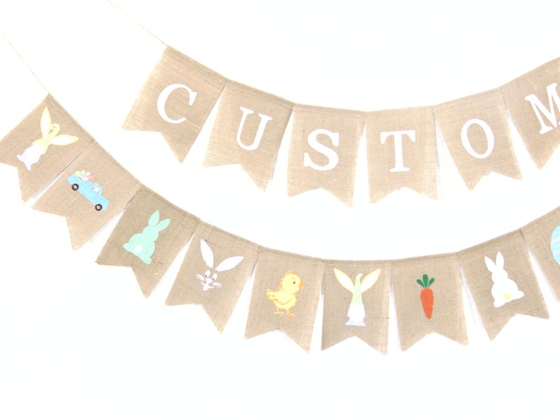 K&ouml;nnte beinhalten: Ein Banner aus Jute mit dem Wort "CUSTOM" in wei&szlig;en Buchstaben. Das Banner ist mit Ostern-Motiven verziert, darunter Hasen, K&uuml;ken, Karotten und ein Osterei.