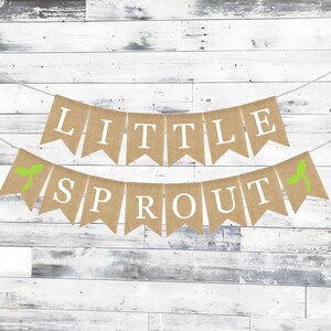 May include: A burlap banner with green leaves and the text "Little Sprout" in white letters. The banner is strung on a white background.