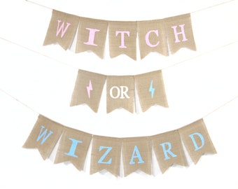 May include: A rustic burlap banner spelling out "WITCH OR WIZARD" in pink, white, and blue lettering. The banner is strung on a white string, with lightning bolt symbols. Ideal for a Halloween or fantasy-themed celebration.