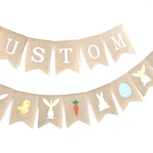 K&ouml;nnte beinhalten: Ein Banner aus Jute mit dem Wort "CUSTOM" in wei&szlig;en Buchstaben. Ein zweites Jutebanner zeigt Bilder zum Thema Ostern, darunter Hasen, K&uuml;ken, Karotten und Eier.