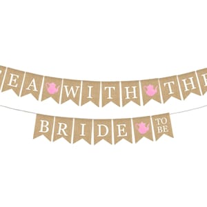 May include: A burlap banner with the text "Tea with the Bride to Be" in white letters. The banner has pink teapots on each of the flags.