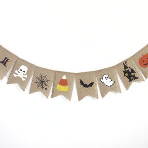 Puede incluir: Una guirnalda de arpillera con tem&aacute;tica de Halloween con varios iconos festivos. La guirnalda presenta un sombrero de bruja, botas, una calavera, una telara&ntilde;a, caramelos de ma&iacute;z, un murci&eacute;lago, un fantasma, una casa embrujada, una calabaza y un gato negro.