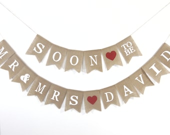 May include: A burlap banner with the text "Mr. & Mrs. Soon to be David" in white letters. The banner has red hearts between the words.