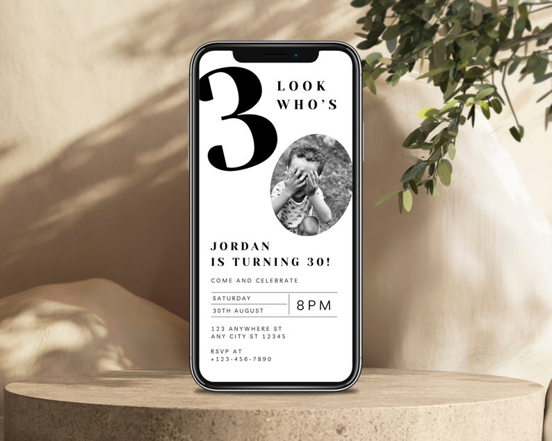 May include: A black and white birthday invitation on a smartphone screen. The invitation says "Look Who's 30!" and includes a photo of a young boy. The invitation also includes the text "Jordan is turning 30!" and details for the event, including the date, time, and location.