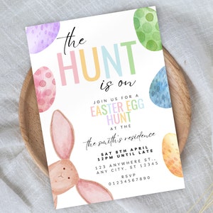 May include: A colourful invitation for an Easter egg hunt. The invitation features a bunny rabbit, pastel coloured eggs, and the text "the HUNT is on". The invitation also includes the date, time, and location of the event.
