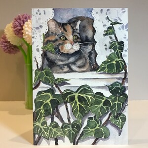 May include: Watercolor painting of a tabby cat peeking through a window with green ivy vines. The cat has green eyes and is looking to the right. The painting is signed in the bottom right corner.