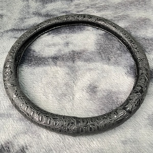 Peut inclure: Un couvre-volant en cuir noir avec un motif floral en relief.