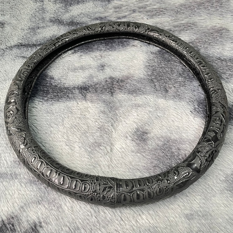 Peut inclure: Un couvre-volant en cuir noir avec un motif floral en relief.