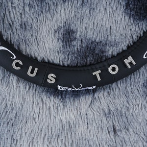 May include: Black steering wheel cover with the words "Custom Tom" in silver rhinestones.