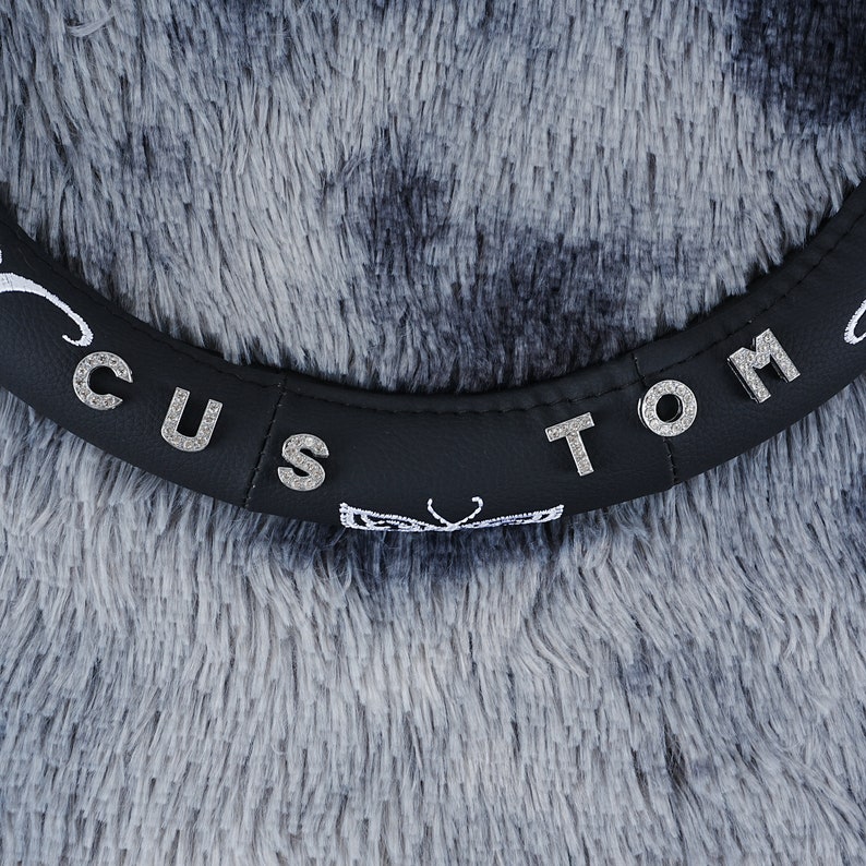 May include: Black steering wheel cover with the words "Custom Tom" in silver rhinestones.