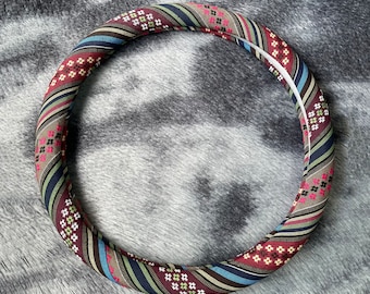 May include: A colorful steering wheel cover with a geometric pattern in shades of brown, blue, green, red, and white.